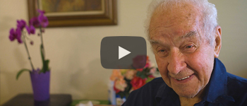 image of an elderly man in a room with flowers behind him